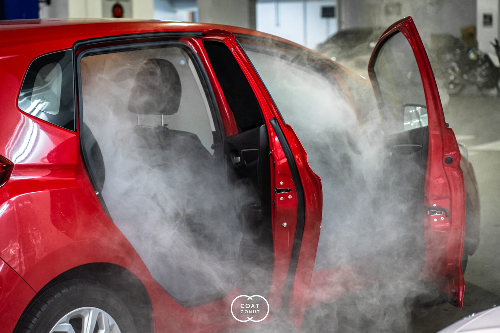Steam cleaning the interior of a red car at Coatconut