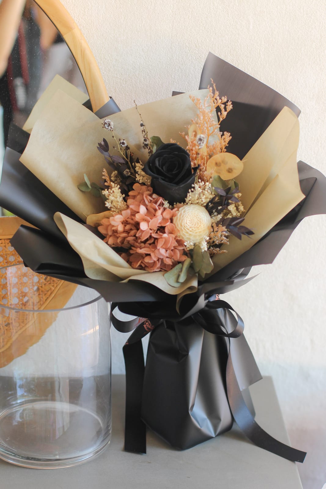 A Dawn Q preserved bouquet with a black rose, terracotta hydrangea and cream dahlia in black and kraft wrap
