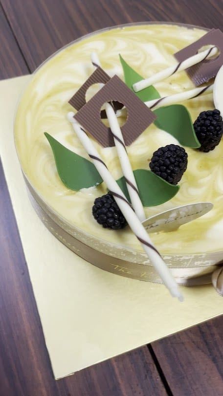 The Patissier cake topped with blackberries and a chocolate disc